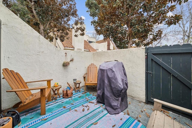 wooden terrace featuring area for grilling, a fenced backyard, and a gate