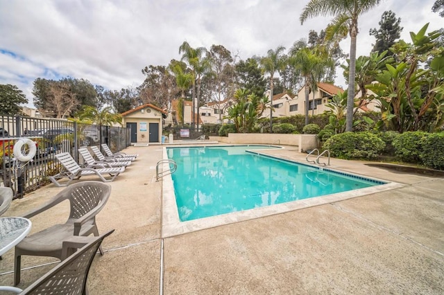 community pool with a patio area and fence