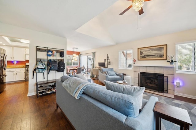 living area with dark wood-style floors, a tiled fireplace, baseboards, and a wealth of natural light