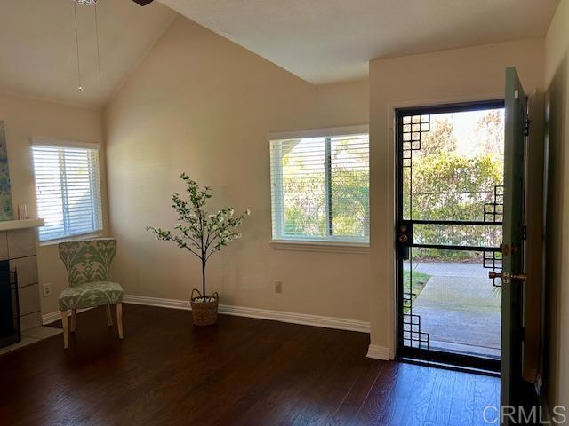 unfurnished room featuring lofted ceiling, a fireplace, wood finished floors, and baseboards