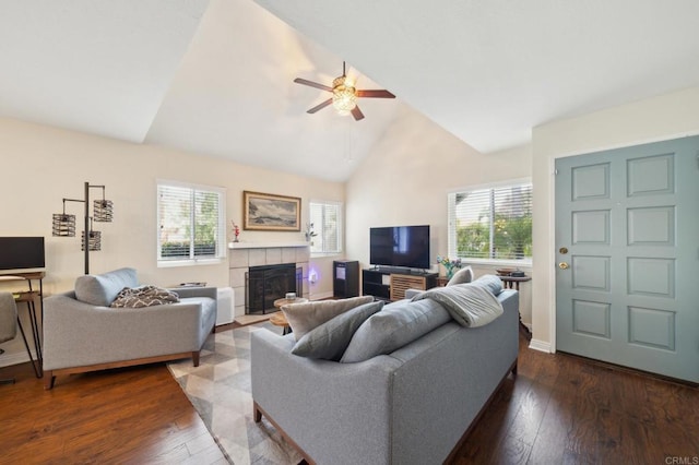 living area featuring a healthy amount of sunlight, dark wood-style floors, a ceiling fan, and a tile fireplace