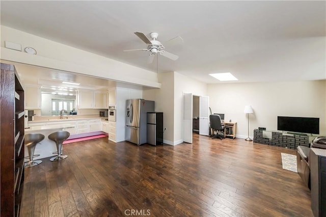 interior space with a skylight, white cabinets, a kitchen breakfast bar, dark hardwood / wood-style flooring, and stainless steel refrigerator with ice dispenser