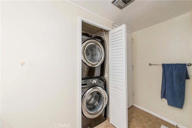 laundry room with stacked washer and clothes dryer and light tile patterned floors