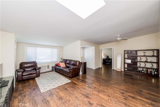 living room with ceiling fan, dark hardwood / wood-style flooring, a wall mounted AC, and vaulted ceiling with skylight