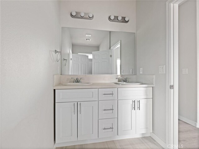 full bath with double vanity, baseboards, and a sink