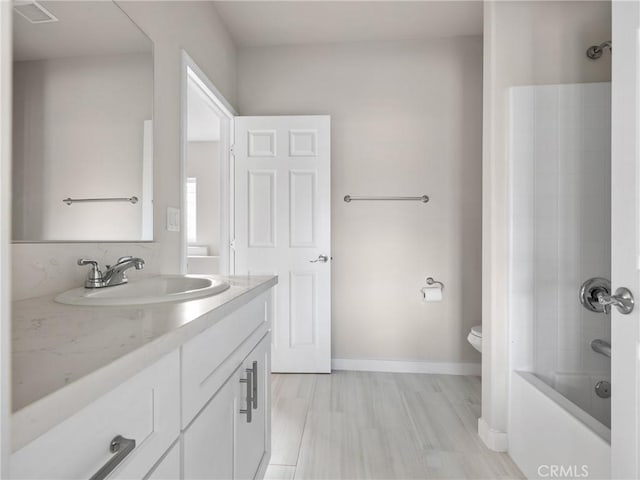 bathroom with baseboards, toilet,  shower combination, and vanity