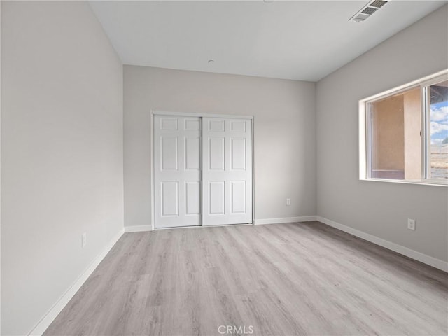 unfurnished bedroom with light wood-style flooring, baseboards, visible vents, and a closet