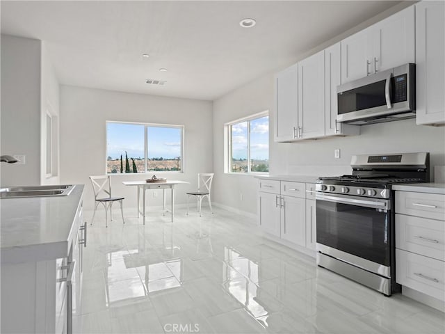 kitchen with visible vents, a sink, stainless steel appliances, light countertops, and white cabinetry