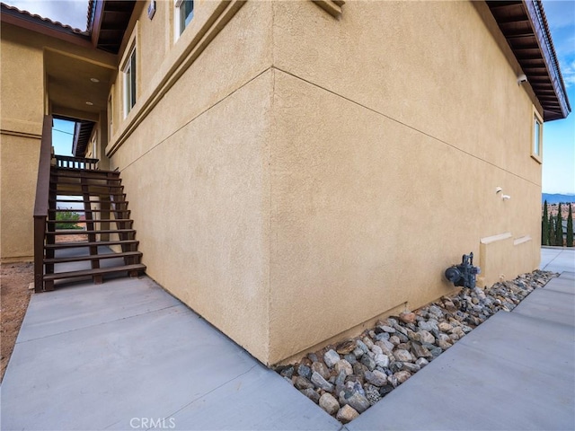 view of side of home with stucco siding and stairs