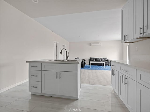 kitchen featuring baseboards, gray cabinets, a sink, light countertops, and open floor plan