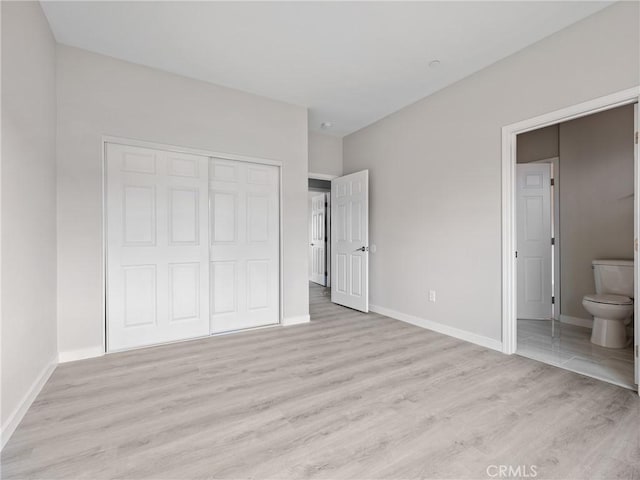 unfurnished bedroom with light wood finished floors, baseboards, and a closet