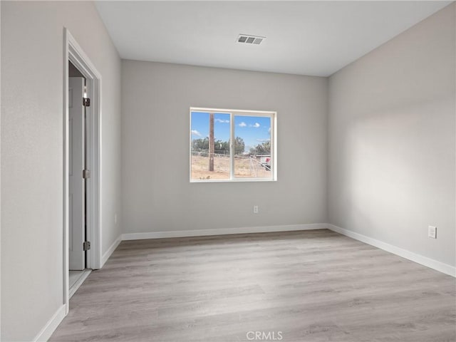 empty room featuring visible vents, baseboards, and wood finished floors