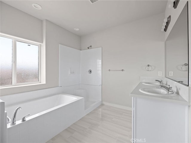 bathroom with walk in shower, double vanity, a bath, and a sink