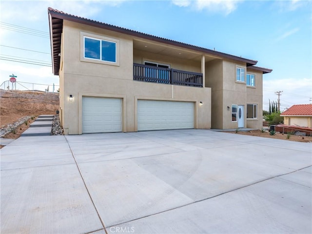 view of front of house featuring stucco siding, an attached garage, concrete driveway, and a balcony