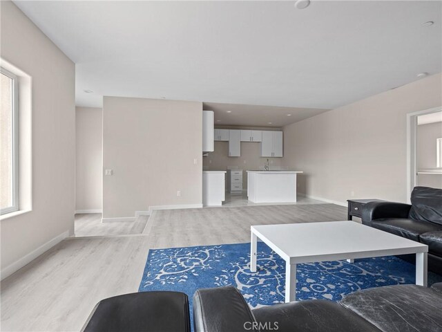 living area with light wood-style flooring and baseboards