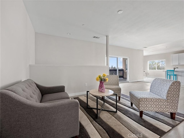 living room with light wood finished floors, visible vents, and baseboards