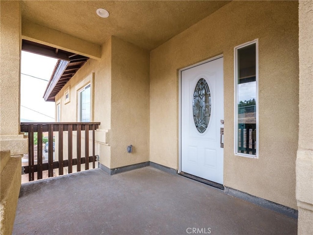 view of exterior entry with a balcony and stucco siding