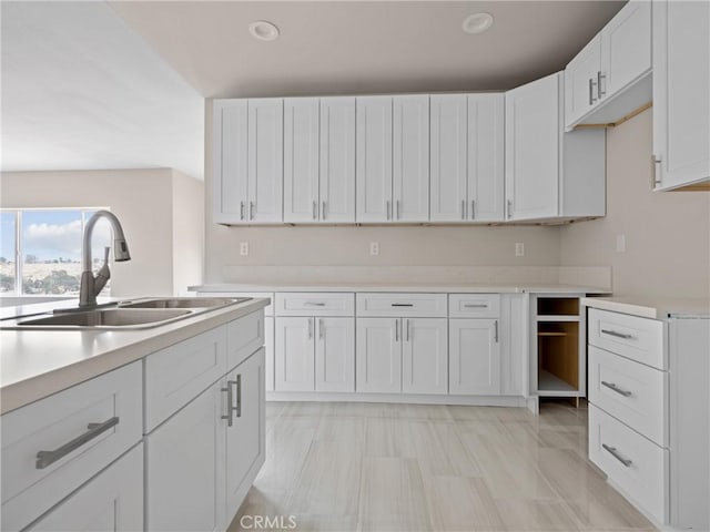 kitchen with recessed lighting, white cabinets, light countertops, and a sink