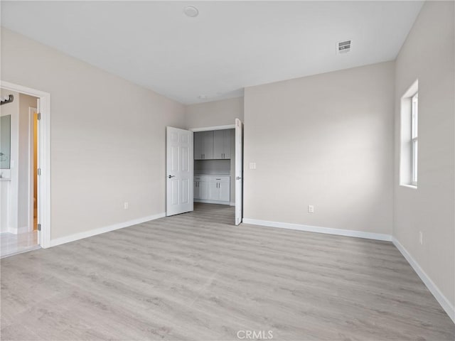 unfurnished bedroom featuring visible vents, light wood-type flooring, and baseboards