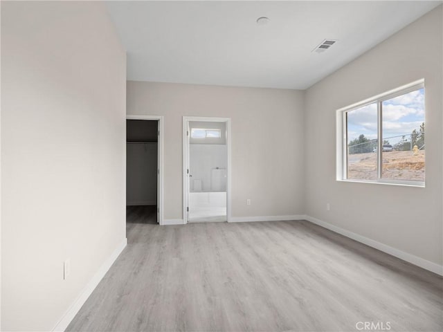 unfurnished room featuring visible vents, light wood-style flooring, and baseboards