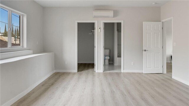 8411 Buckthorn Ave, Hesperia, CA 92345 - unfurnished bedroom featuring an AC wall unit, a walk in closet, wood finished floors, baseboards, and a closet