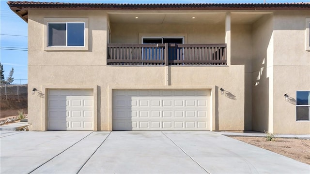 view of front of house with stucco siding, an attached garage, driveway, and a balcony