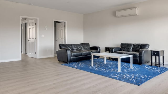 living room featuring baseboards, an AC wall unit, and wood finished floors