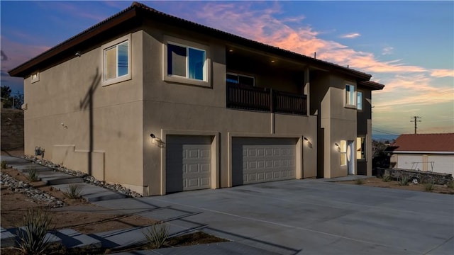 property exterior at dusk featuring stucco siding, a garage, and driveway