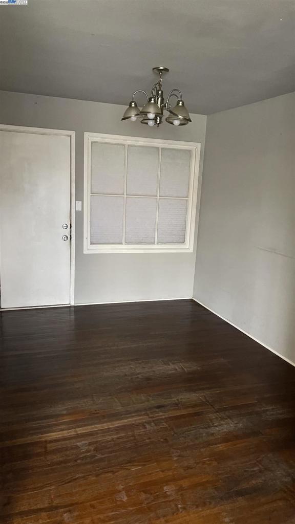 unfurnished dining area with a notable chandelier and dark hardwood / wood-style flooring