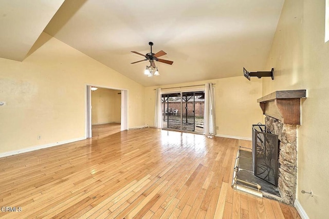 unfurnished living room featuring high vaulted ceiling, a stone fireplace, light hardwood / wood-style floors, and ceiling fan