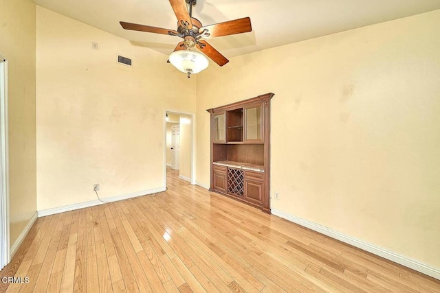 empty room with ceiling fan and light hardwood / wood-style flooring