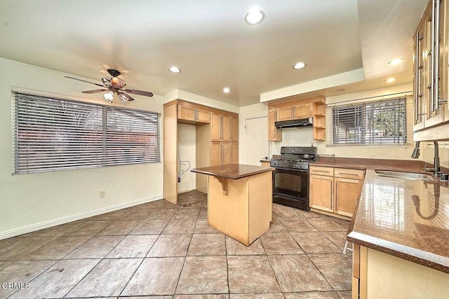 kitchen with a breakfast bar, sink, black gas stove, a kitchen island, and ceiling fan