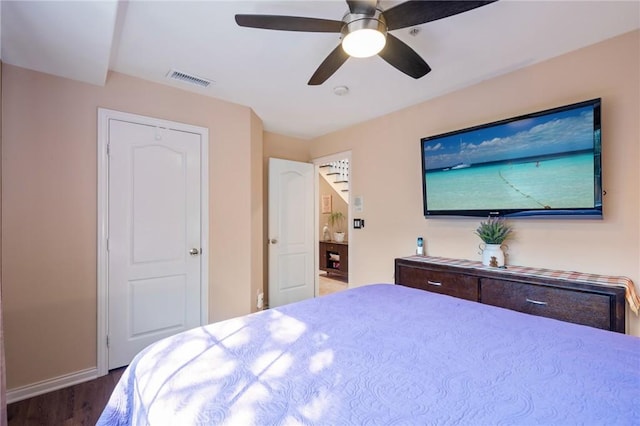 bedroom with baseboards, ceiling fan, visible vents, and wood finished floors