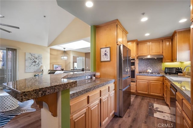 kitchen with tile countertops, appliances with stainless steel finishes, a breakfast bar, under cabinet range hood, and a sink