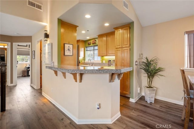 kitchen with tile countertops, dark wood-type flooring, a breakfast bar area, and visible vents