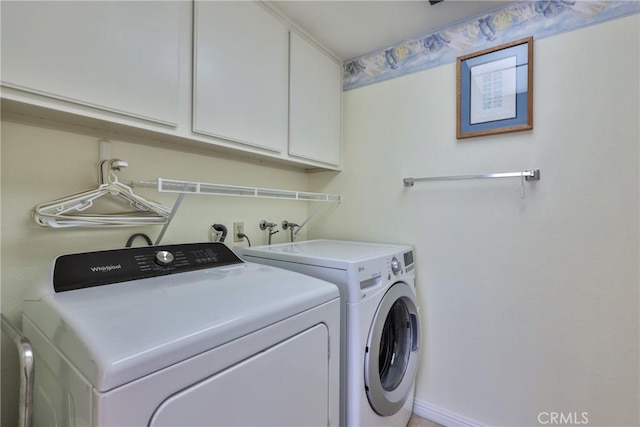 clothes washing area with cabinets and washing machine and clothes dryer