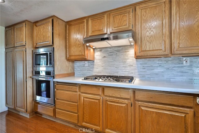 kitchen featuring stainless steel appliances, light hardwood / wood-style floors, and backsplash