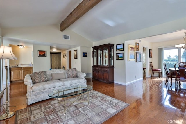 living room featuring hardwood / wood-style flooring, sink, an inviting chandelier, and lofted ceiling with beams