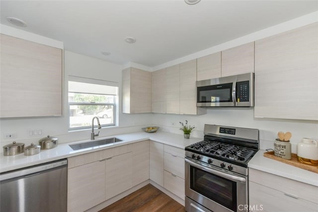 kitchen with light brown cabinetry, sink, dark hardwood / wood-style floors, and appliances with stainless steel finishes