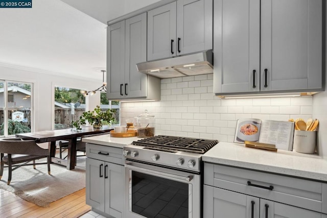 kitchen with gray cabinetry, gas range, light stone countertops, and decorative backsplash