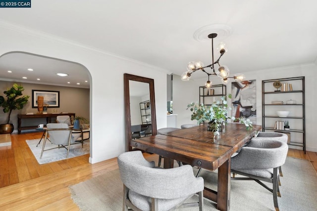 dining space featuring crown molding, a chandelier, and light hardwood / wood-style flooring