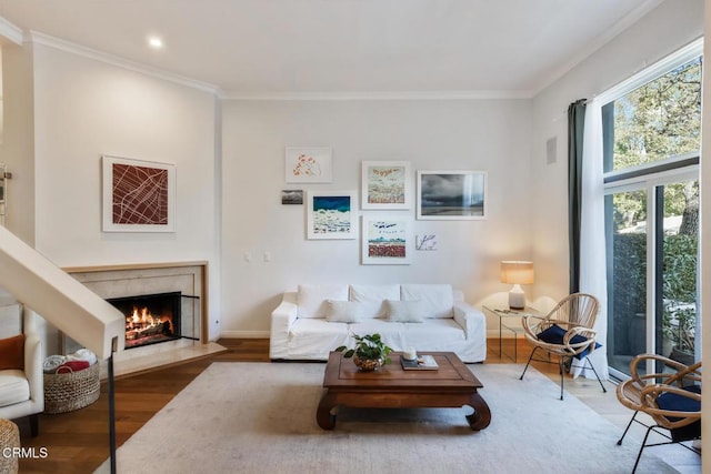 living room with ornamental molding, a tile fireplace, and wood-type flooring