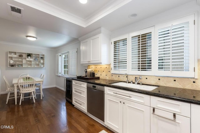 kitchen with white cabinetry, sink, dark stone countertops, ornamental molding, and stainless steel dishwasher