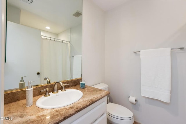 bathroom with walk in shower, vanity, and toilet