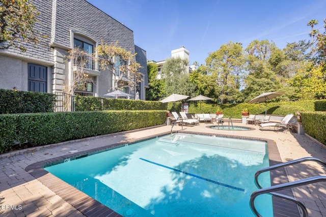 view of swimming pool with a hot tub and a patio