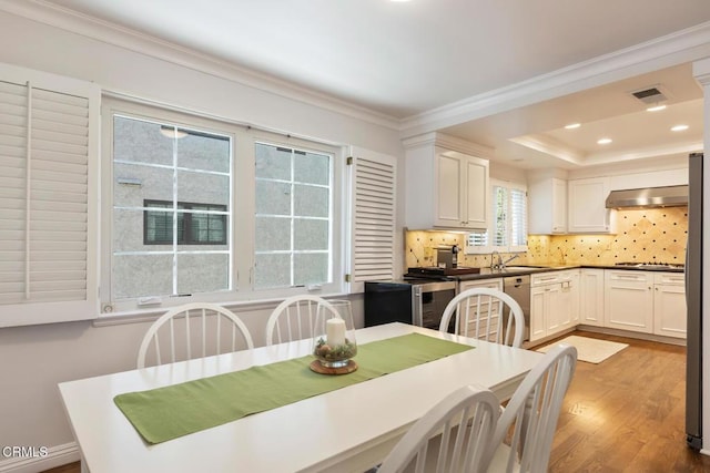 dining room featuring hardwood / wood-style flooring, crown molding, sink, and a tray ceiling