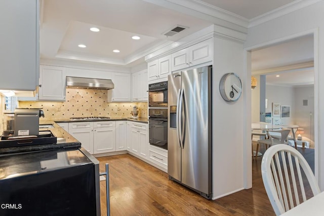 kitchen featuring appliances with stainless steel finishes, wood-type flooring, white cabinets, ornamental molding, and exhaust hood