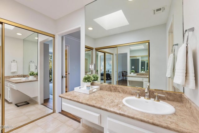 bathroom featuring tile patterned flooring, vanity, and a skylight