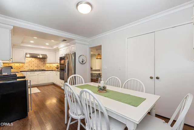 dining room featuring ornamental molding, dark hardwood / wood-style flooring, and a tray ceiling