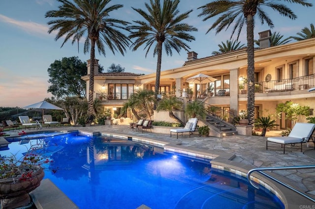 pool at dusk with a patio area